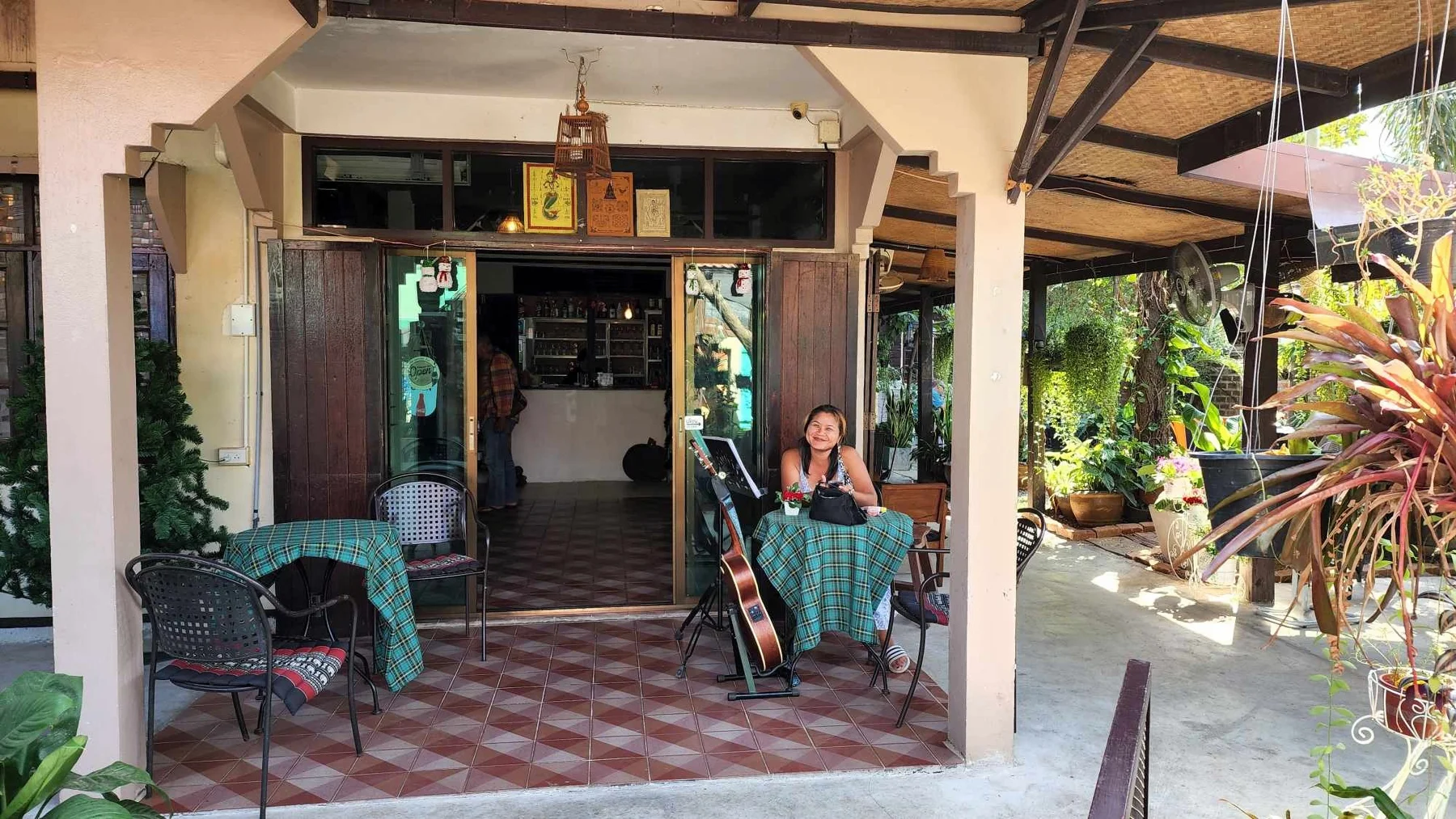 The Outside Inn entrance with shaded tables and tropical plants